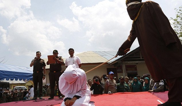 Encolhida de medo em seus joelhos, uma mulher indonésia é chicoteada na frente de uma multidão … porque tinha começado a namorar